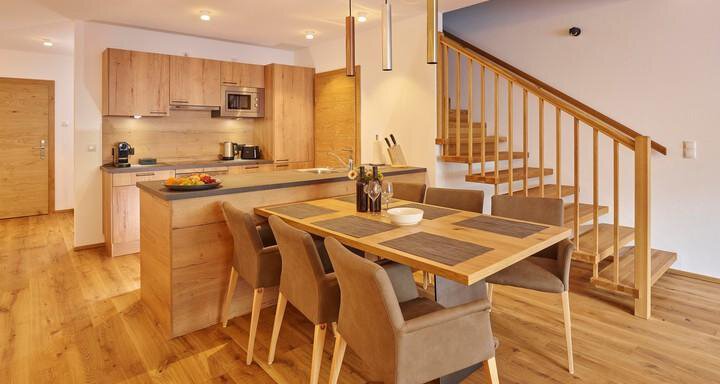 Eine moderne Küche mit Holzmöbeln und einem Esstisch. Die Treppe führt zu einem zweiten Stockwerk. - Alpenappartement Central Valley Penthouse - Längenfeld