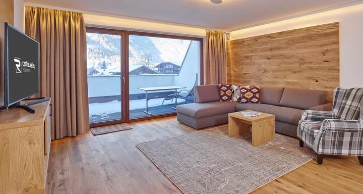 Ein modernes Wohnzimmer mit einem gemütlichen Sofa und einem Sessel. Große Fenster bieten einen schönen Blick auf die Berge. - Alpenappartement Central Valley Penthouse - Längenfeld