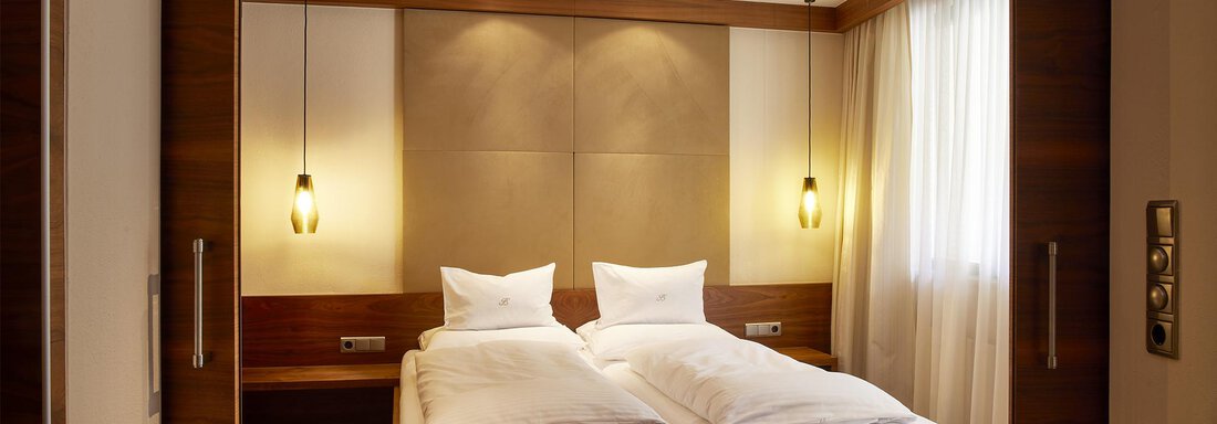 Hotel-Bergwelt-Obergurgl-Hotelsuite-C2 | © Art & Relax Hotel Bergwelt (CC BY) A modern bedroom with two single beds and warm wood tones. The large window front brings a lot of daylight into the room. - Art & Relax Hotel Bergwelt - Obergurgl