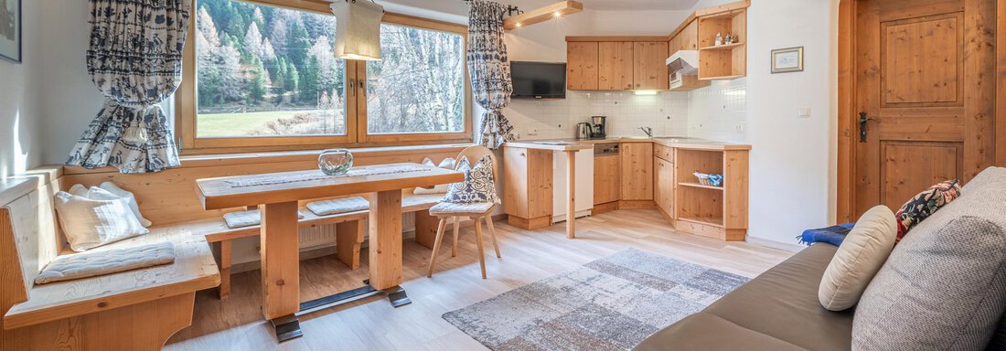 Eine gemütliche Küche mit einem Holzessenbereich und modernen Annehmlichkeiten. Große Fenster bieten einen Blick auf die umliegende Natur. - Ferienwohnung Alt Poschach - Obergurgl 
