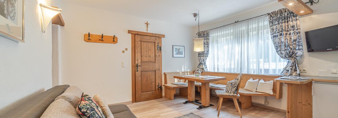 Ein gemütliches Wohnzimmer mit einem Sofa, einem Tisch und Stühlen. Große Fenster lassen viel Licht herein und sorgen für eine einladende Atmosphäre. - Ferienwohnung Alt Poschach - Obergurgl 