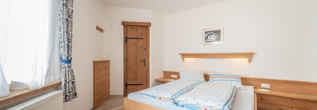 Ein gemütliches Schlafzimmer mit einem großen Doppelbett und holzfarbenen Möbeln. Das Zimmer hat ein ruhiges Ambiente mit natürlichem Licht durch das Fenster. - Ferienwohnung Alt Poschach - Obergurgl 