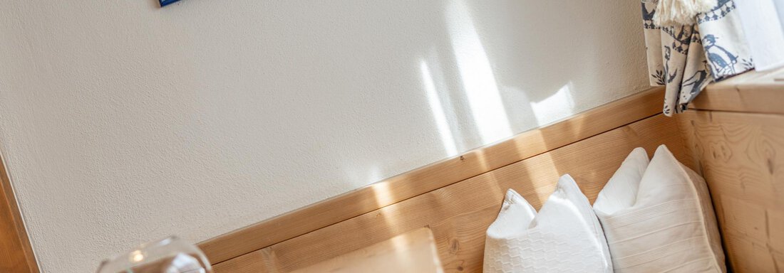 Ein gemütlicher Essbereich mit hellen Wänden und Holzdetails. Auf dem Tisch steht eine Glasvase, und die Fensterdekoration bietet ein heimisches Flair. - Ferienwohnung Alt Poschach - Obergurgl 