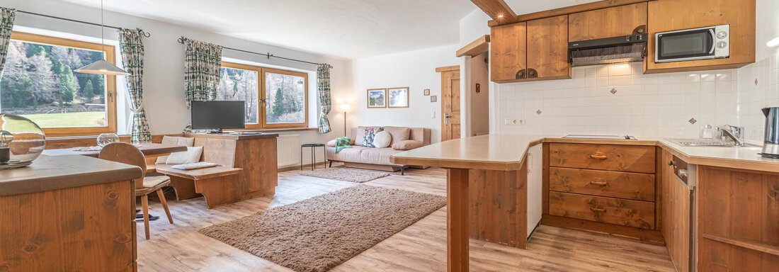 Eine helle, einladende Küche mit Holzschränken und moderner Ausstattung. Der Wohnbereich ist offen gestaltet und bietet viel Platz mit Blick nach draußen. - Ferienwohnung Alt Poschach - Obergurgl 