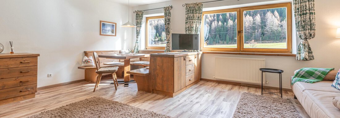 Ein gemütliches Wohnzimmer mit Holzmöbeln und großen Fenstern. Der Boden ist mit einem Teppich ausgelegt und es gibt eine angenehme Atmosphäre. - Ferienwohnung Alt Poschach - Obergurgl 
