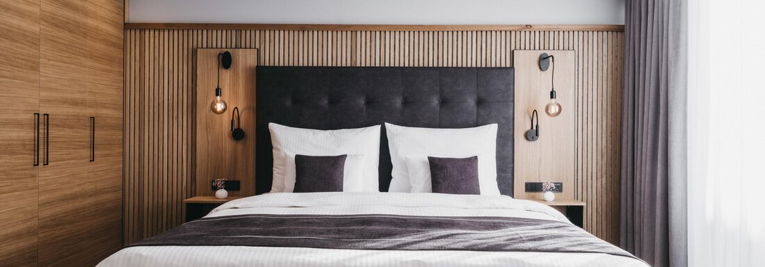 A modern bedroom with a large double bed and stylish wooden furniture.  
Natural light flows through the window curtains, creating an inviting atmosphere. - The Crystal VAYA Unique - Obergurgl 