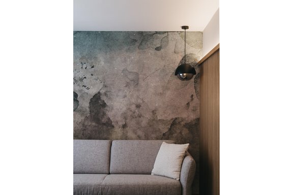An elegant living room with a gray wall and a comfortable sofa. A modern lamp hangs from the ceiling, providing cozy light. - The Crystal VAYA Unique - Obergurgl 