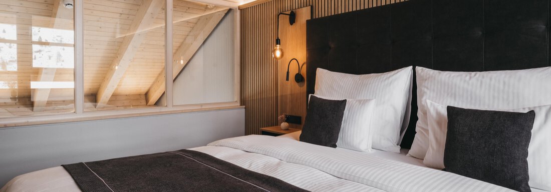 A modern bedroom with a large double bed and elegant pillows. Large windows provide plenty of daylight and a cozy atmosphere. - The Crystal VAYA Unique - Obergurgl 