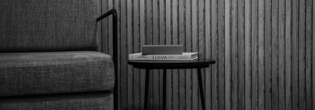 A modern living room with a gray armchair and a small table. The table holds a few books, while the wall is paneled with vertical wood panels. - The Crystal VAYA Unique - Obergurgl 