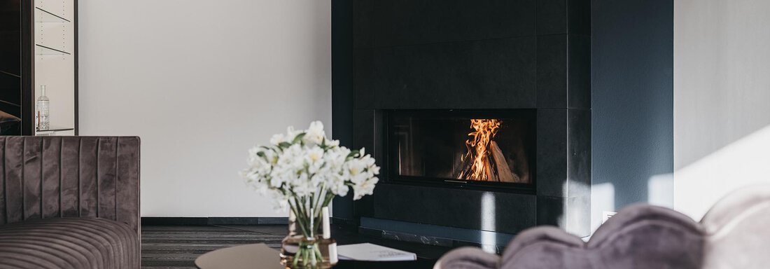 A modern living room with an elegant sofa and a coffee table. The fireplace creates a cozy atmosphere. - The Crystal VAYA Unique - Obergurgl 