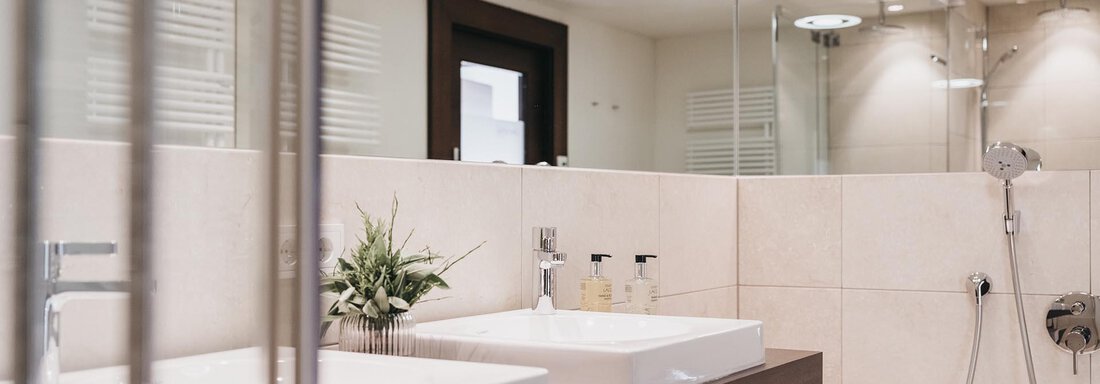 A modern bathroom with two sinks and a large mirror. The elegant furnishings and soft lighting create a relaxing atmosphere. - The Crystal VAYA Unique - Obergurgl 