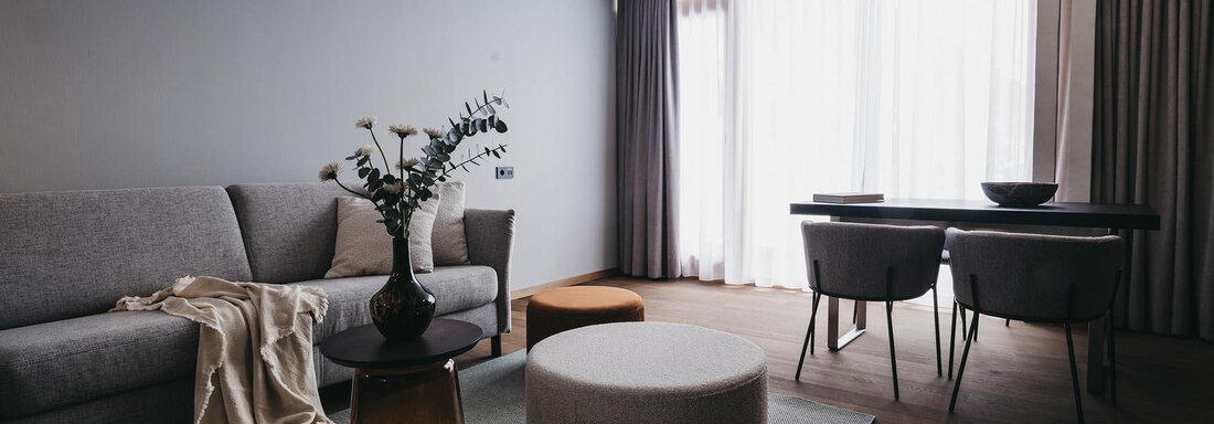 VAYACrystal A modern living room with a gray couch and a dining table. Large windows let in plenty of light. - The Crystal VAYA Unique - Obergurgl