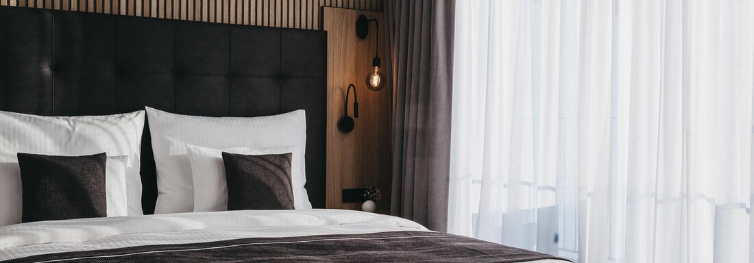 A modern bedroom with a large bed and elegant bedding. Large windows let in plenty of daylight and create a bright atmosphere. - The Crystal VAYA Unique - Obergurgl 