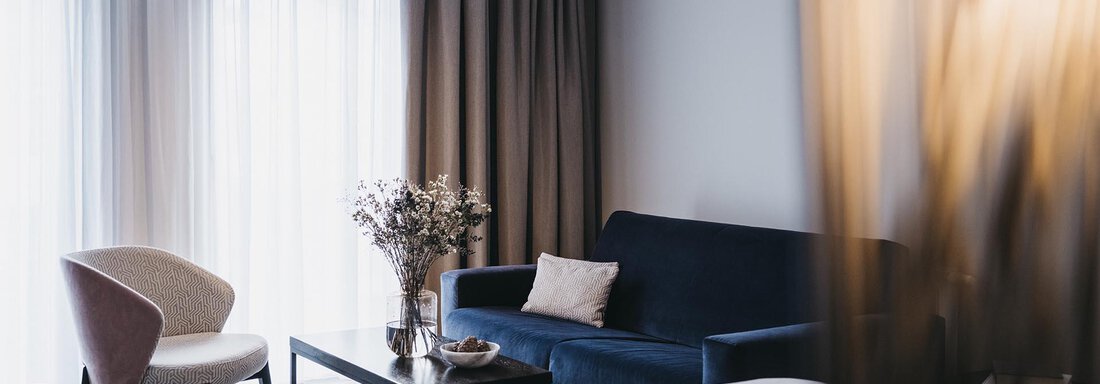 A modern room with a cozy bed and a sofa.  
Large windows allow plenty of daylight in and create an inviting atmosphere. - The Crystal VAYA Unique - Obergurgl 