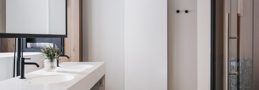 A modern bathroom with an elegant washbasin and a light grey color scheme. The glass shower and the towel radiator complement the stylish design. - The Crystal VAYA Unique - Obergurgl 
