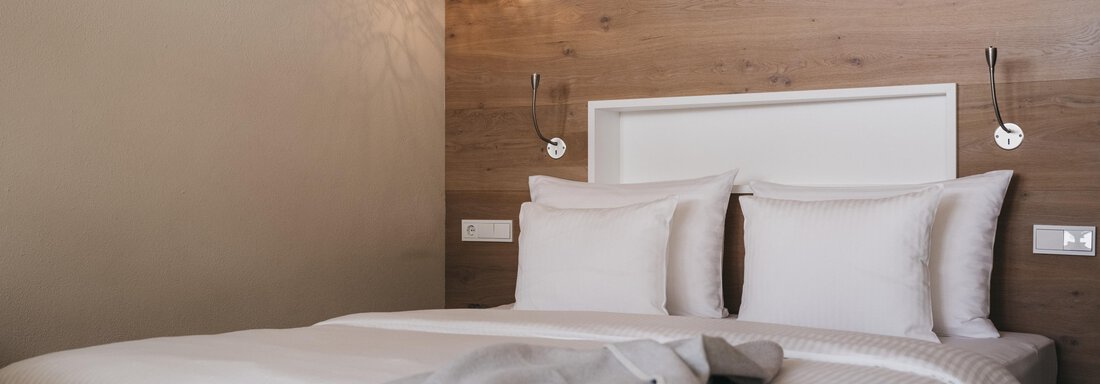 A modern bedroom with a comfortable bed and stylish decorations. The walls are paneled with wood, creating a cozy atmosphere. - The Crystal VAYA Unique - Obergurgl 