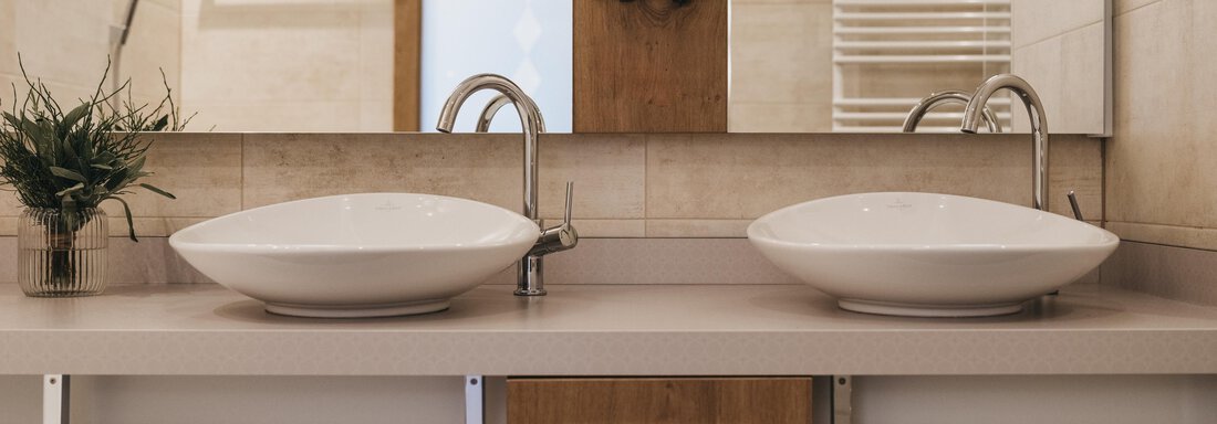 A modern bathroom with two sinks and large mirrors. Elegant wood and light accents create an inviting atmosphere. - The Crystal VAYA Unique - Obergurgl 
