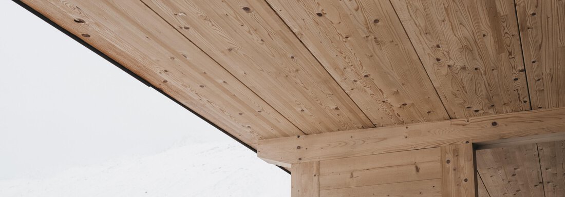 A wooden ceiling in a modern building. Snow-capped mountains are visible in the background. - The Crystal VAYA Unique - Obergurgl 