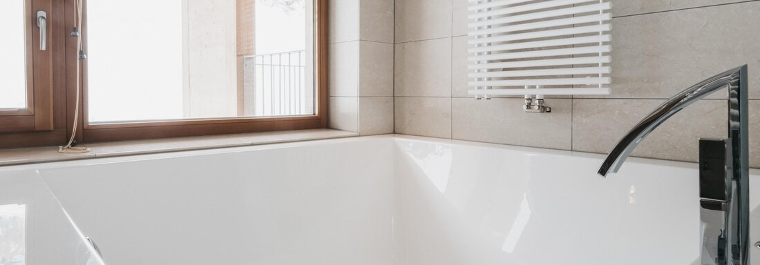 A modern bathroom with a large, white bathtub. The window lets in plenty of daylight. - The Crystal VAYA Unique - Obergurgl 