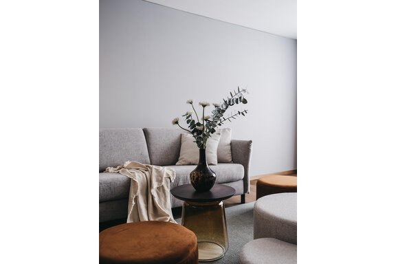 A modernly furnished living room with a gray sofa and a round table. On the table stands a vase with eucalyptus. - The Crystal VAYA Unique - Obergurgl 