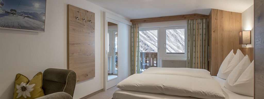 Ein gemütliches Hotelzimmer mit einem großen Bett und moderner Einrichtung. Große Fenster sorgen für viel Licht und einen Blick nach draußen. - Pension Michael - Obergurgl 