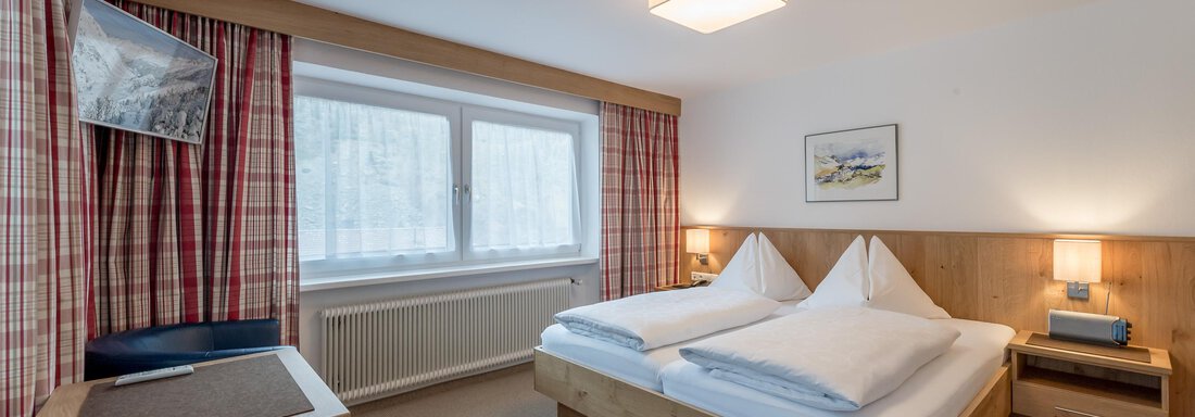 Ein gemütliches Hotelzimmer mit zwei Betten und einem modernen Design. Große Fenster sorgen für viel Tageslicht und eine angenehme Atmosphäre. - Pension Michael - Obergurgl 