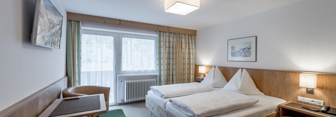 Ein modernes Hotelzimmer mit zwei Betten und einer gemütlichen Sitzecke. Große Fenster sorgen für viel Tageslicht. - Pension Michael - Obergurgl 