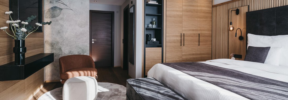 A modern bedroom with a comfortable bed and elegant wooden furniture. The soft colors and the light create an inviting atmosphere. - The Crystal VAYA Unique - Obergurgl 