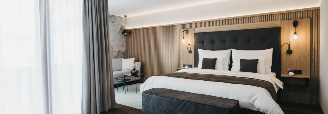 Grand Deluxe II | © The Crystal VAYA Unique (CC C) A modern hotel room with a large bed and stylish hardwood floors. The windows let in plenty of light and the decor is cozy and inviting. - The Crystal VAYA Unique - Obergurgl
