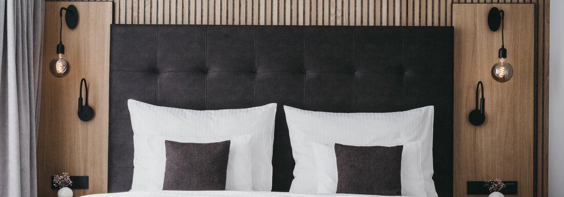 Junior Penthouse | © The Crystal VAYA Unique (CC C) A modern bedroom with a large, upholstered headboard. The stylish decor includes elegant lighting and cozy pillows. - The Crystal VAYA Unique - Obergurgl