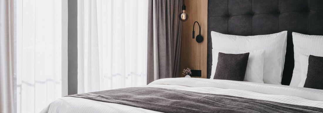 A modern bedroom with a stylish bed and elegant bedding. Large windows let in plenty of daylight. - The Crystal VAYA Unique - Obergurgl 
