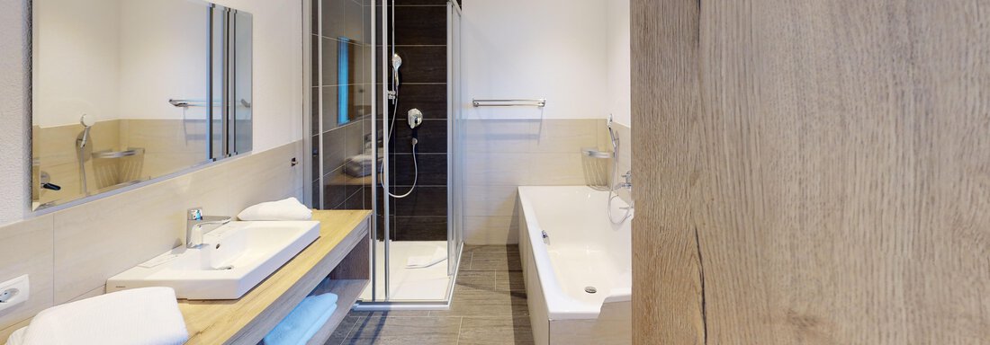 Ein modernes Badezimmer mit einer Fußbodendusche und einer freistehenden Badewanne. Helle Farbtöne und Holzdetails schaffen eine einladende Atmosphäre. - A CASA "Rubin Chalet & Studio Resort" - Sölden