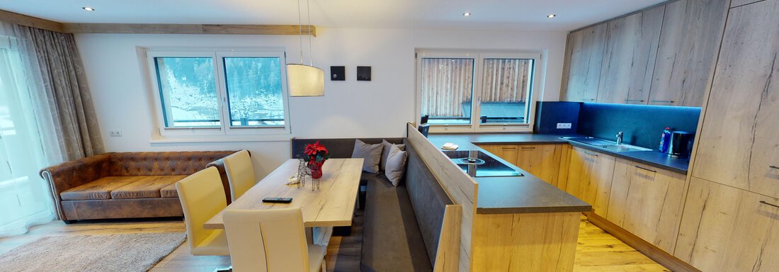 Eine moderne Küchen- und Wohnbereich mit Holzmöbeln und viel natürlichem Licht. Der Esstisch ist elegant gedeckt und eine gemütliche Couch lädt zum Entspannen ein. - A CASA "Rubin Chalet & Studio Resort" - Sölden