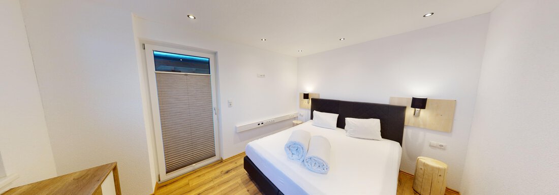 Ein modernes Schlafzimmer mit einem großen Doppelbett und zwei Kissen. Helle Wände und Holzböden sorgen für eine angenehme Atmosphäre. - A CASA "Rubin Chalet & Studio Resort" - Sölden
