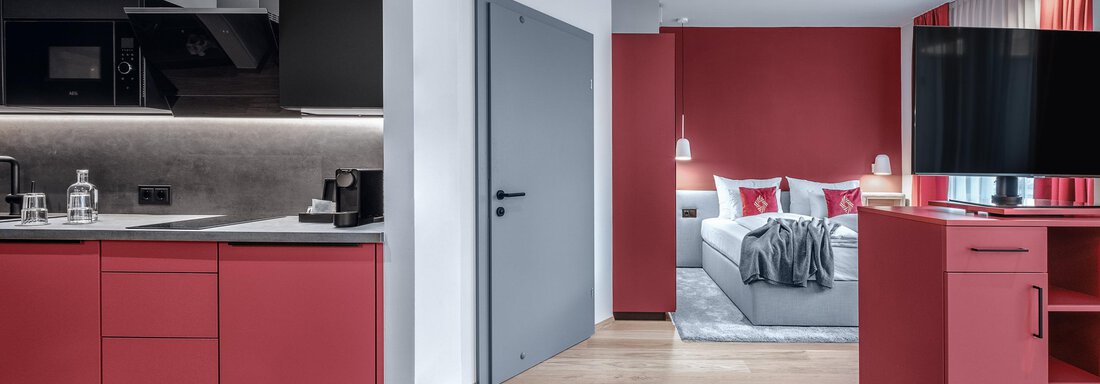 Apartment-resort-im-oetztal -the-secret-soelden-Sm Ein modernes Zimmer mit einer offenen Küchenzeile und roten Akzenten. Der Bereich ist stilvoll eingerichtet und bietet eine gemütliche Atmosphäre. - AlpenParks The Secret Sölden - Sölden