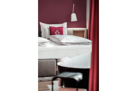 Ein stilvolles Schlafzimmer mit einem bequemen Bett und einer modernen Badewanne. Die Wände sind in einem warmen Purpurton gestrichen, und es gibt gemütliche Dekorationselemente. - AlpenParks The Secret Sölden - Sölden