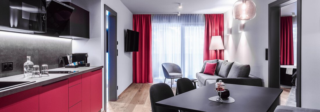 Moderne Wohnung mit roter Küchenzeile und stilvollem Essbereich. Gemütliches Wohnzimmer mit viel Licht und modernen Möbeln. - AlpenParks The Secret Sölden - Sölden
