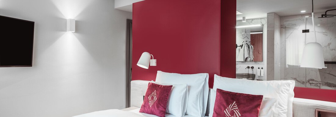 Ein modernes Hotelzimmer mit einem Doppelbett und roten Akzenten. Die Raumgestaltung ist hell und einladend. - AlpenParks The Secret Sölden - Sölden