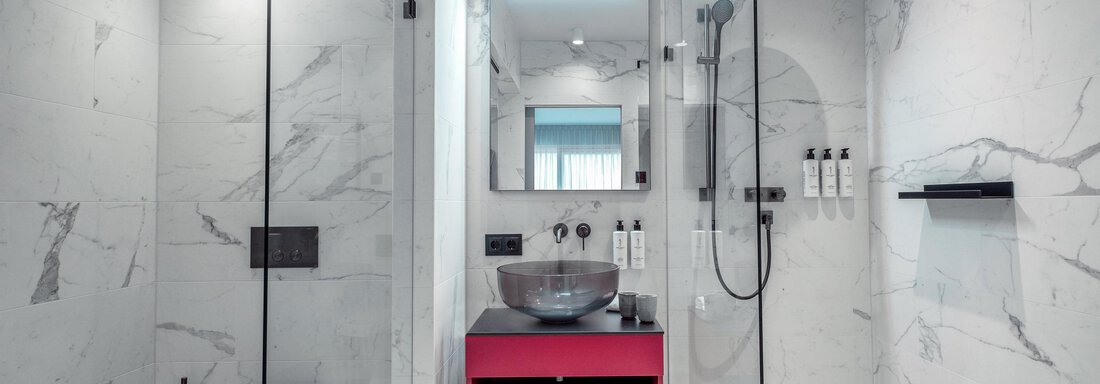 Ein modernes Badezimmer mit Glasduschkabine und elegantem Marmorlook. Ein markantes pinkes Regal hebt sich von der neutralen Farbpalette ab. - AlpenParks The Secret Sölden - Sölden