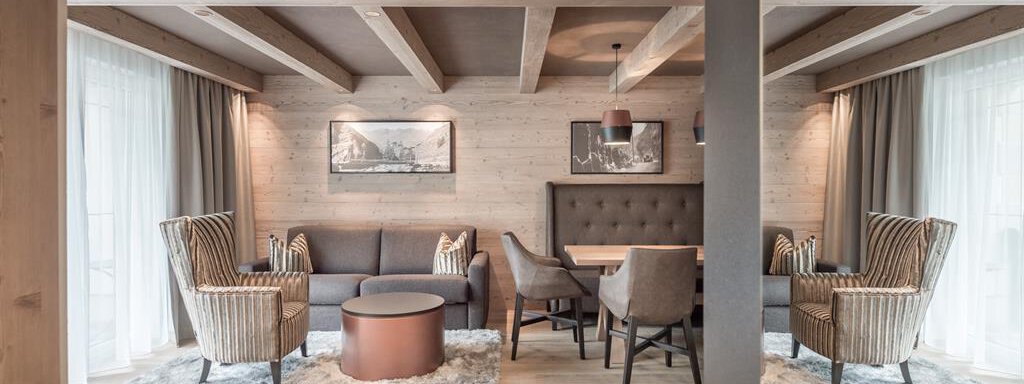 SMALL SECRET Ein modernes Wohnzimmer mit Holzdecken und großen Fenstern. Gemütliche Sessel und ein Esstisch schaffen eine einladende Atmosphäre. - AlpenParks The Secret Sölden - Sölden