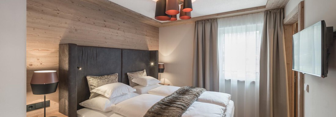 SMART SECRET Ein modernes Schlafzimmer mit einem großen Bett und stilvollen Möbeln. Das Zimmer ist hell und freundlich, mit Holzdetails und einem gemütlichen Ambiente. - AlpenParks The Secret Sölden - Sölden