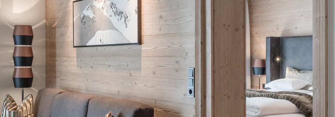 Ein modernes Hotelzimmer mit Holzwänden und einer eleganten Einrichtung. Das Zimmer ist gemütlich und gut beleuchtet, mit einem Blick auf ein Kunstwerk. - AlpenParks The Secret Sölden - Sölden