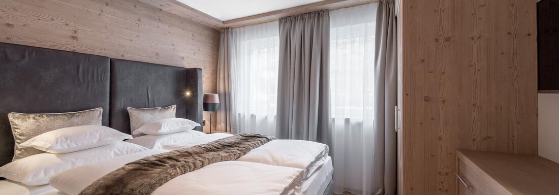 LARGE SECRET Ein gemütliches Schlafzimmer mit einem großen Doppelbett und eleganter Bettwäsche. Die Holzverkleidung und das sanfte Licht schaffen eine warme Atmosphäre. - AlpenParks The Secret Sölden - Sölden