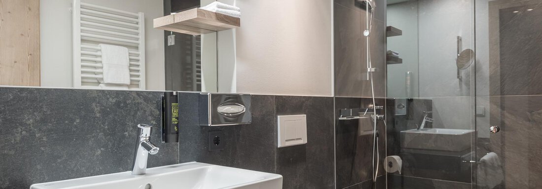 Ein modernes Badezimmer mit eleganten Armaturen. Die Dusche ist mit Glaswänden abgetrennt und die Ausstattung ist schlicht und stilvoll. - AlpenParks The Secret Sölden - Sölden