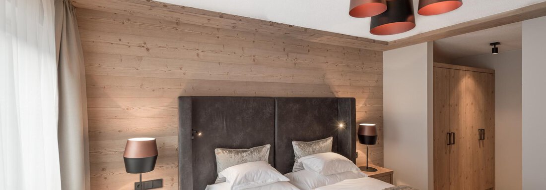 Ein stilvolles Schlafzimmer mit einem Doppelbett und Holzverkleidung. Verschiedene Lichtquellen setzen einen modernen Akzent im Raum. - AlpenParks The Secret Sölden - Sölden