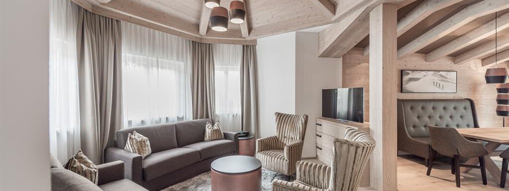 EXTRA LARGE PLUS SECRET Ein modernes Wohnzimmer mit Holzdetails und einem gemütlichen Ambiente. Die Einrichtung umfasst eine gemütliche Couch und stilvolle Sessel um einen runden Tisch. - AlpenParks The Secret Sölden - Sölden