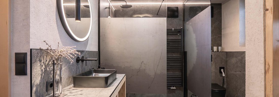 Ein modernes Badezimmer mit eleganter Dusche und minimalistischer Einrichtung. Die Wände sind schick gestaltet, und ein großer Spiegel sorgt für eine helle Atmosphäre. - Apart Reinstadler - Sölden