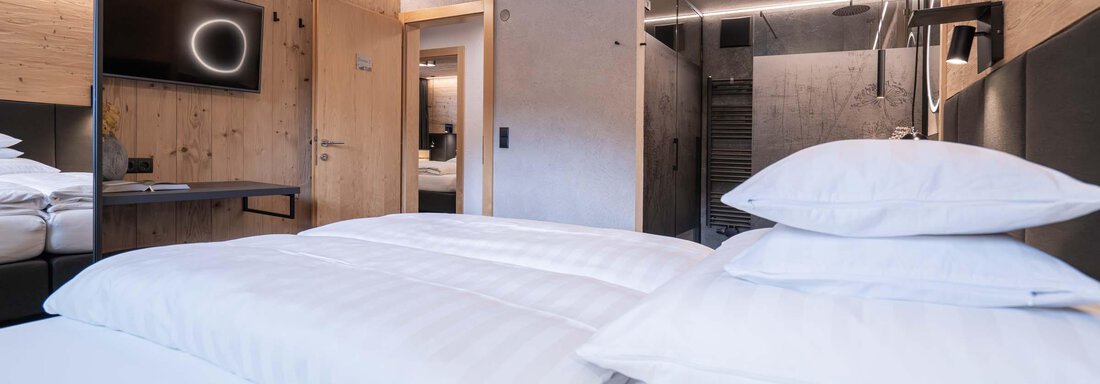 Ein modernes Hotelzimmer mit Holzverkleidung und gemütlichem Bett. Der Raum verfügt über einen Fernseher und ein elegantes Badezimmer. - Apart Reinstadler - Sölden