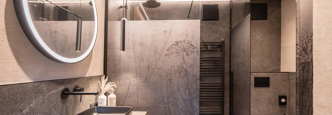 Ein modernes Badezimmer mit einer stilvollen Dusche und einer großen runden Spiegelbeleuchtung. Die Wände sind in neutralen Farbtönen gehalten und es gibt elegante Sanitäranlagen. - Apart Reinstadler - Sölden