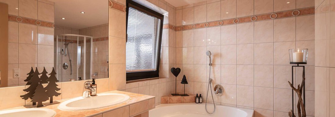 Ein modernes Badezimmer mit einer Badewanne und einer Dusche. Helle Fliesen und stilvolle Dekoration schaffen eine einladende Atmosphäre. - Apart Reinstadler - Sölden
